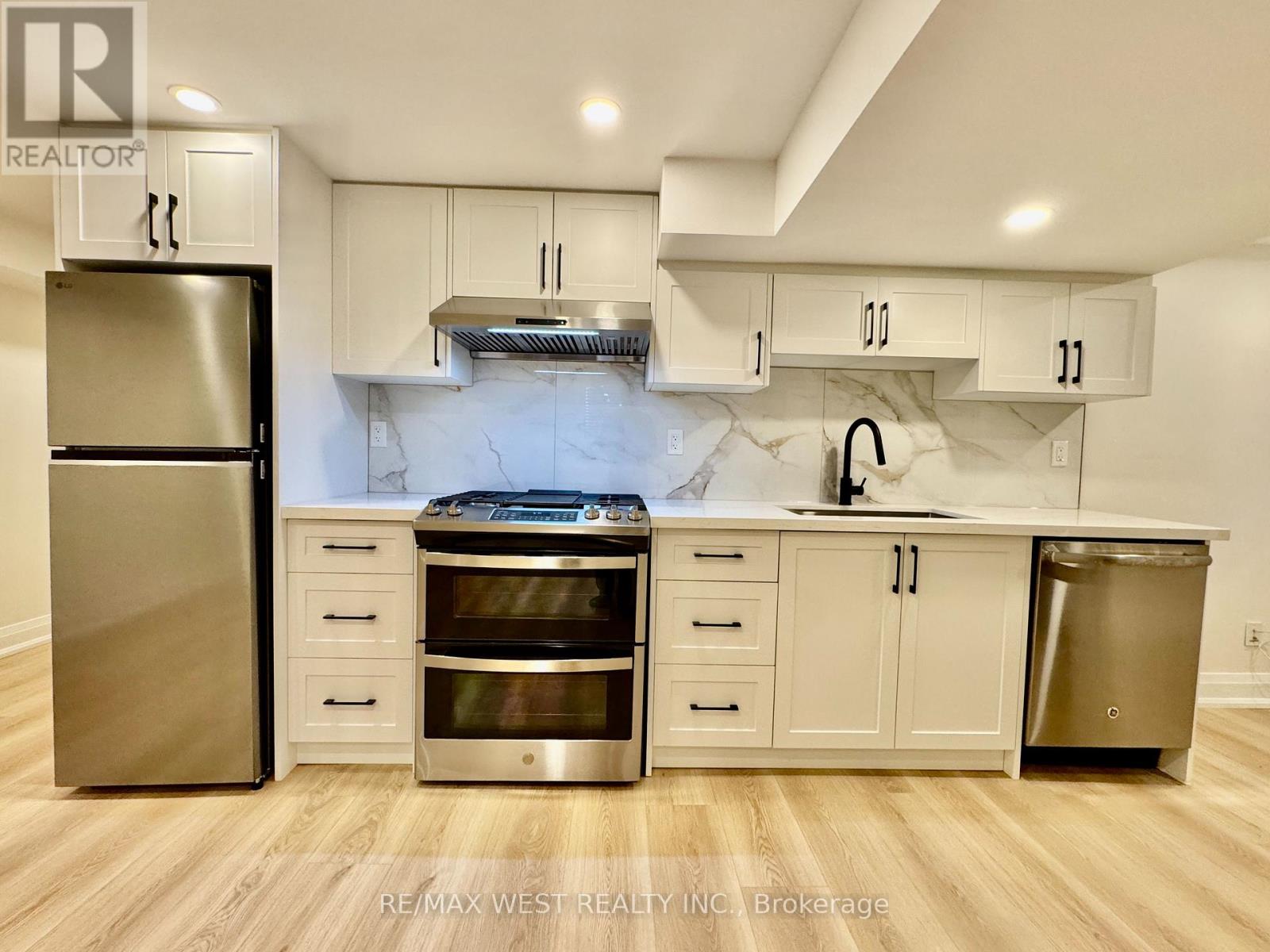 A kitchen with a refrigerator, oven, and cabinets.