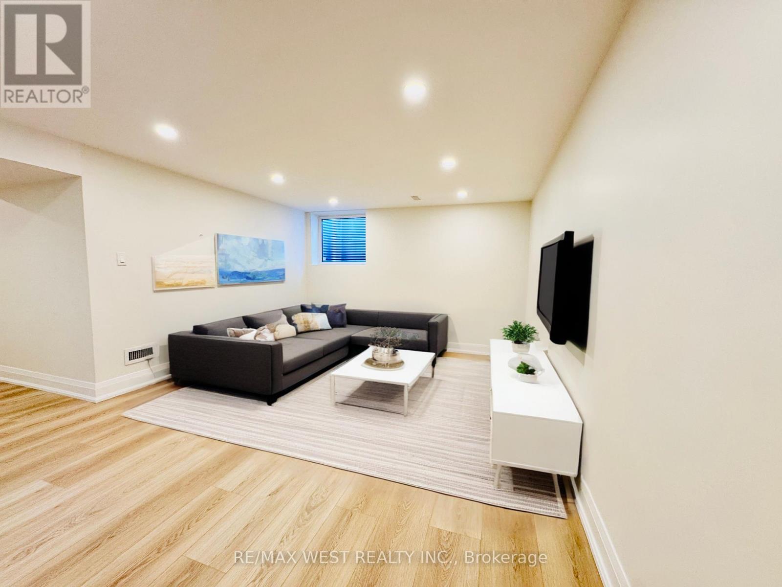 A modern living room with a black sofa and a television on the wall.