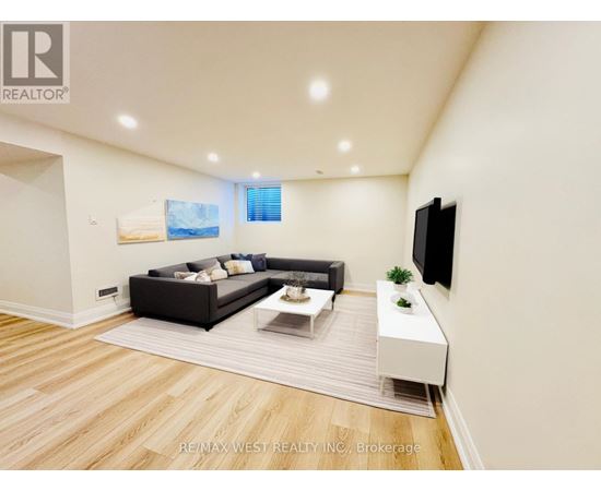 A modern living room with a black sofa and a television on the wall.