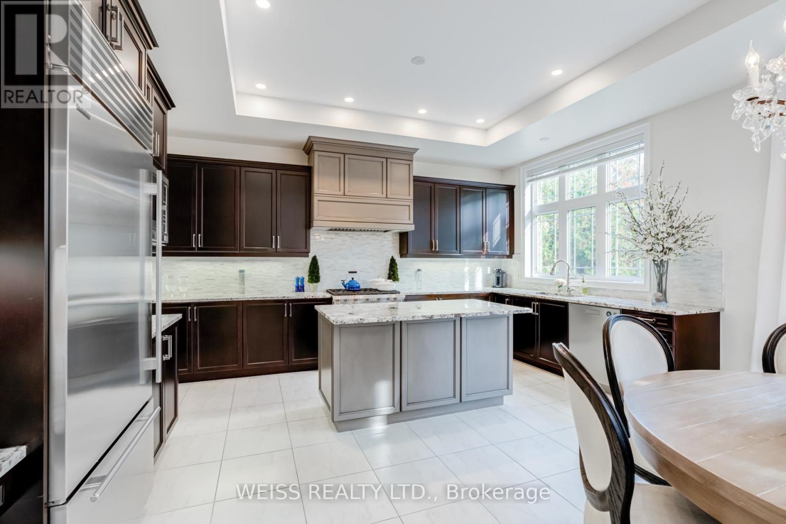 A modern kitchen with a large island and a refrigerator on the left.