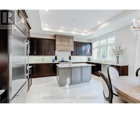 A modern kitchen with a large island and a refrigerator on the left.