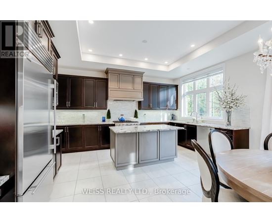 A modern kitchen with a large island and a refrigerator on the left.