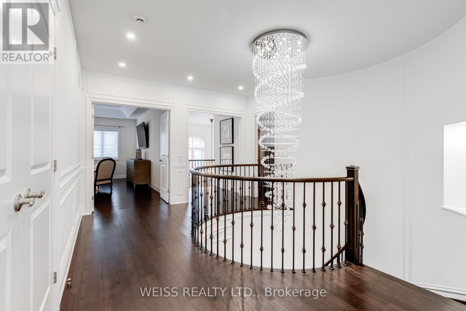 A chandelier hangs from the ceiling in a spacious room with a spiral staircase.