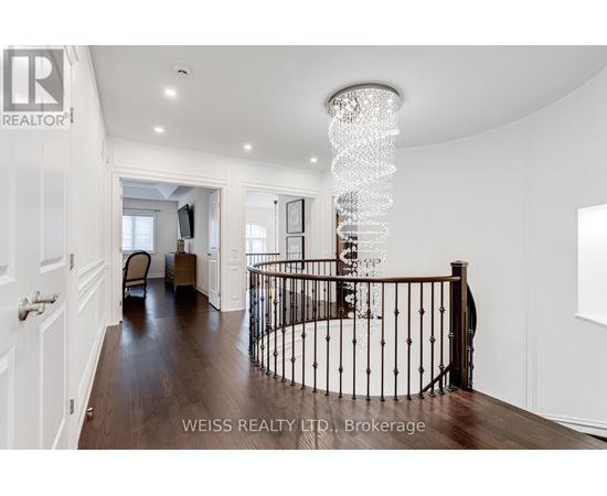 A chandelier hangs from the ceiling in a spacious room with a spiral staircase.