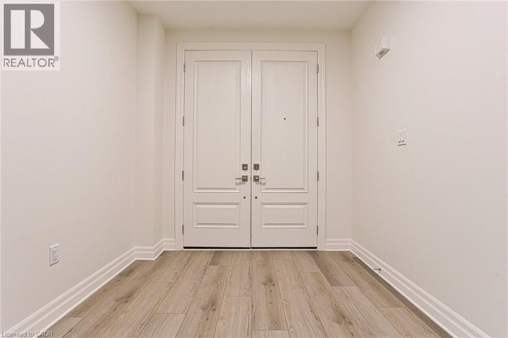 A white door with a black handle is in the middle of a room with wooden flooring.