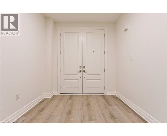 A white door with a black handle is in the middle of a room with wooden flooring.