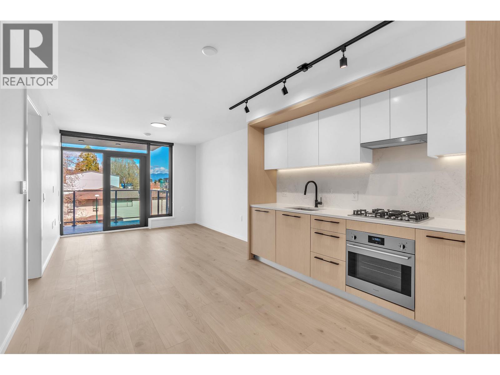 A modern kitchen with wooden floors and white cabinets.
