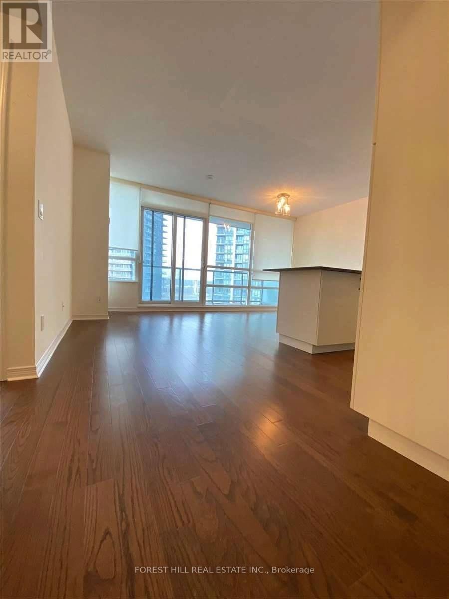 A spacious room with wooden flooring and a large window.