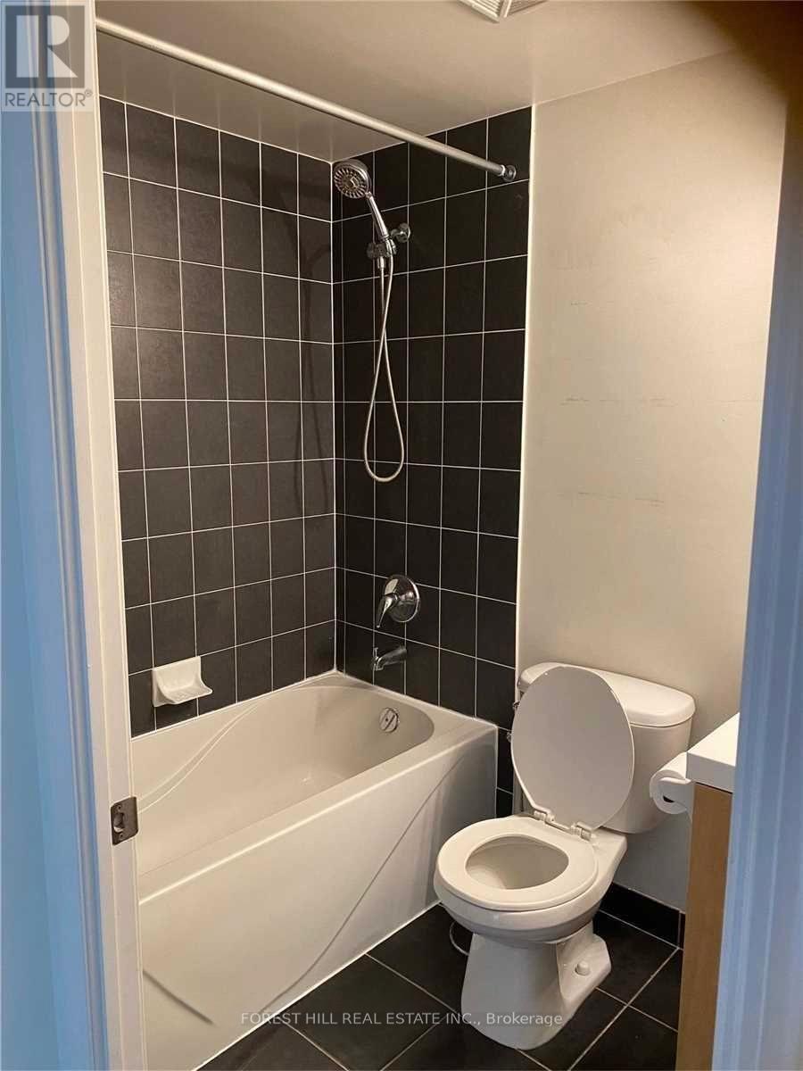 A small bathroom with a toilet, tub, and tiled walls.