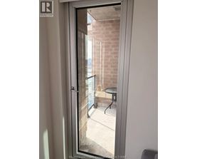 A glass door with a handle and a window showing a balcony with a table and chairs.