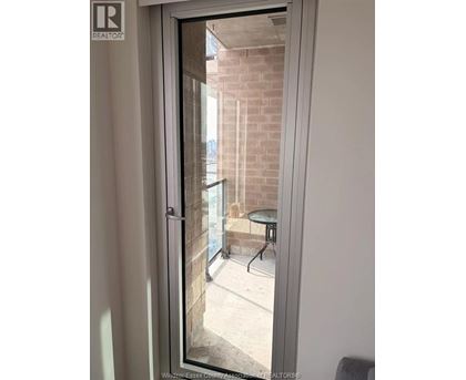 A glass door with a handle and a window showing a balcony with a table and chairs.