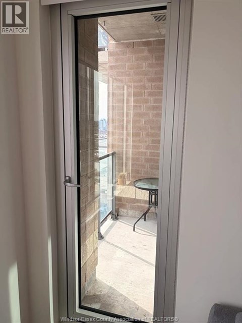 A glass door with a handle and a window showing a balcony with a table and chairs.