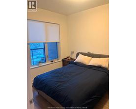 A bedroom with a bed, nightstand, and window.