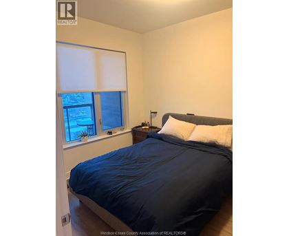 A bedroom with a bed, nightstand, and window.