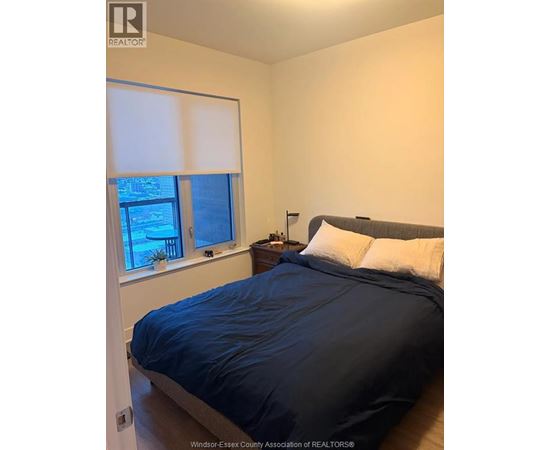 A bedroom with a bed, nightstand, and window.
