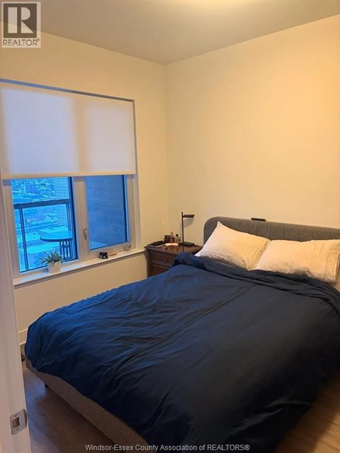 A bedroom with a bed, nightstand, and window.