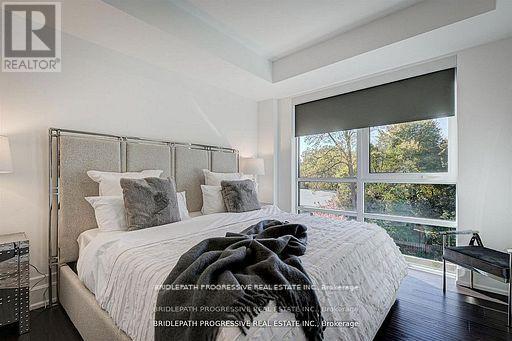 A bedroom with a large bed and a balcony overlooking trees.