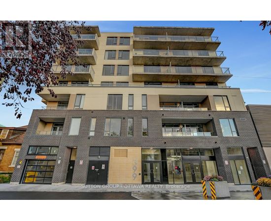 A modern multi-story building with a flat roof and a balcony on the top floor.
