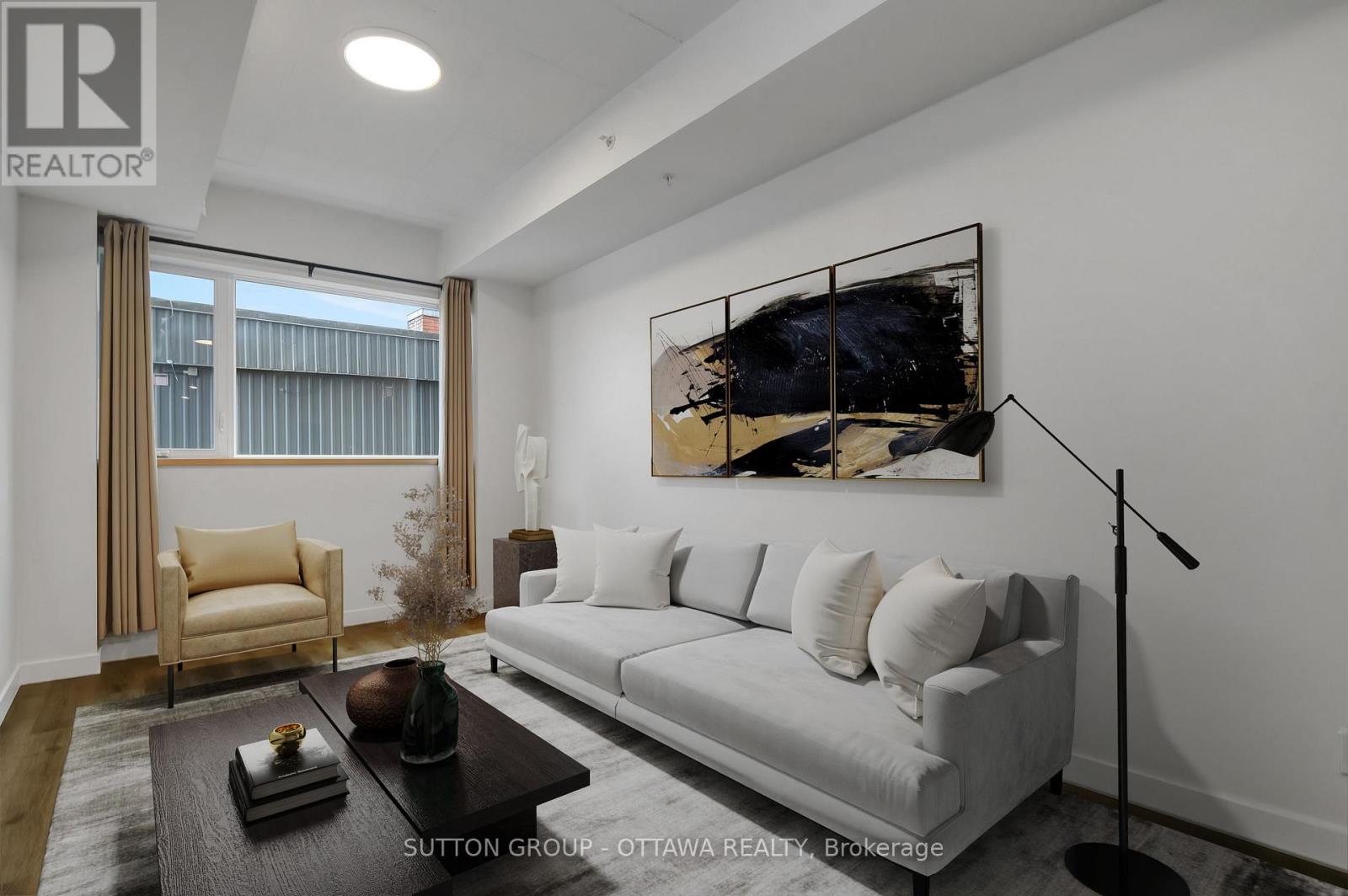 A modern living room with a grey sofa, a coffee table, and a large abstract painting on the wall.