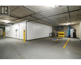 A large, empty warehouse space with a white wall and yellow safety lines on the floor.