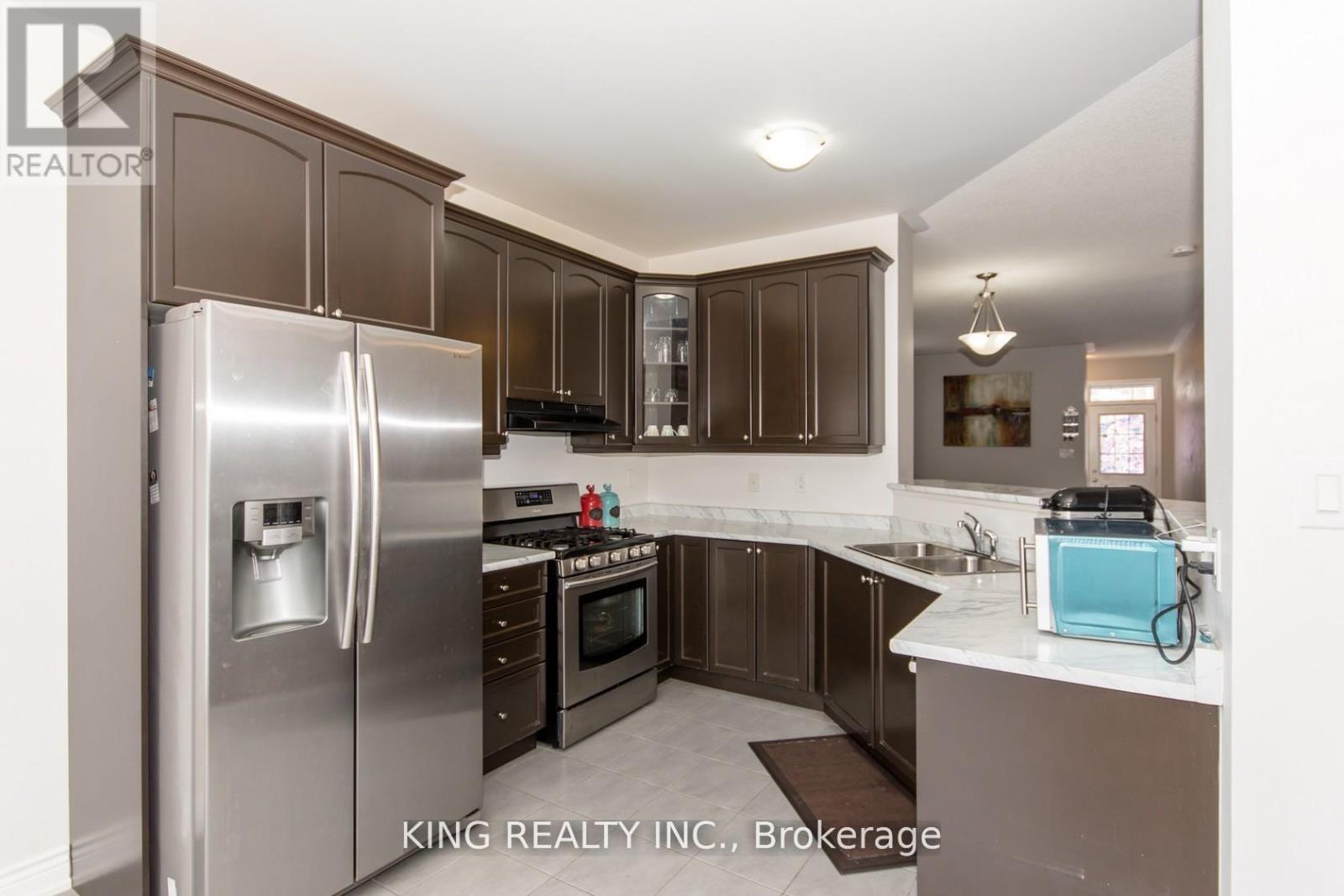 A kitchen with a refrigerator, oven, microwave, and sink.