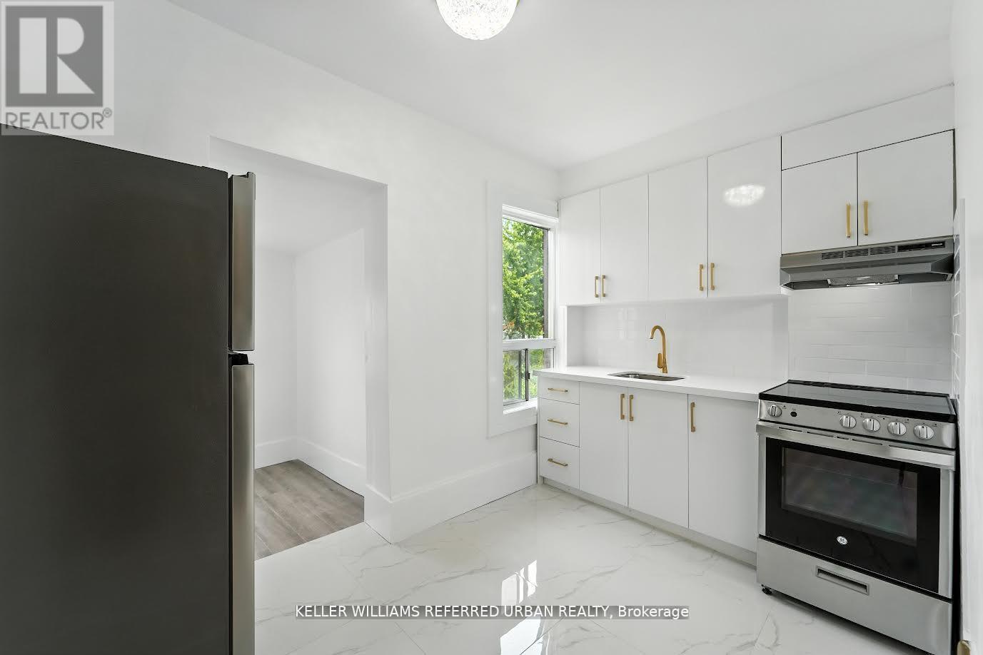 A kitchen with white cabinets and a black refrigerator.
