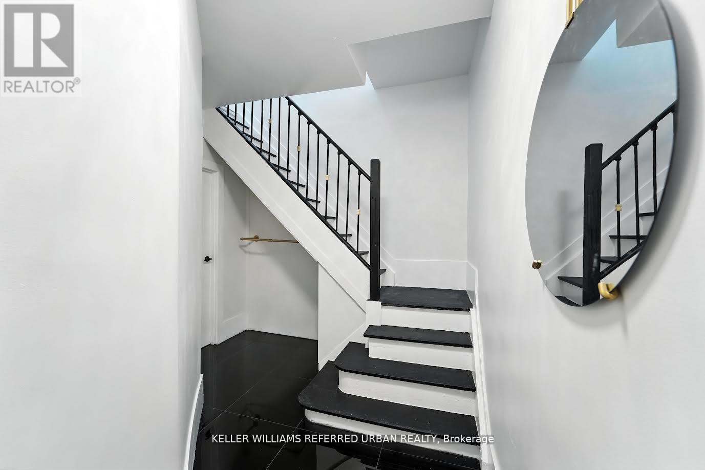 A staircase with a black railing and steps leading up to a white door.