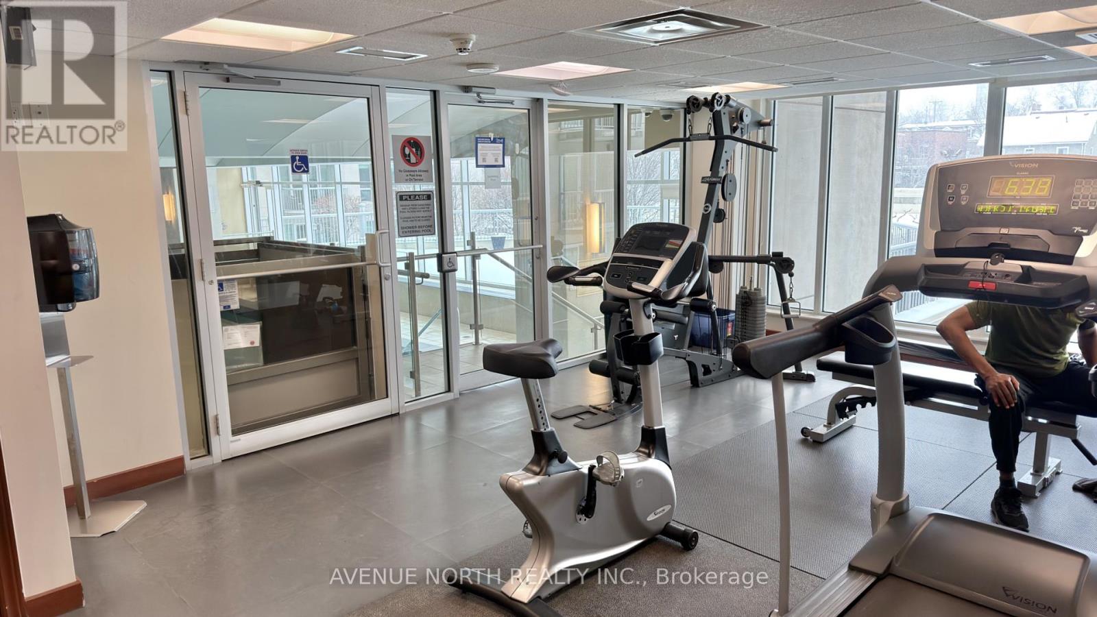 A gym with a treadmill, weights, and a television.