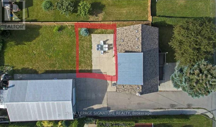 A real estate sign is on a building in a field.