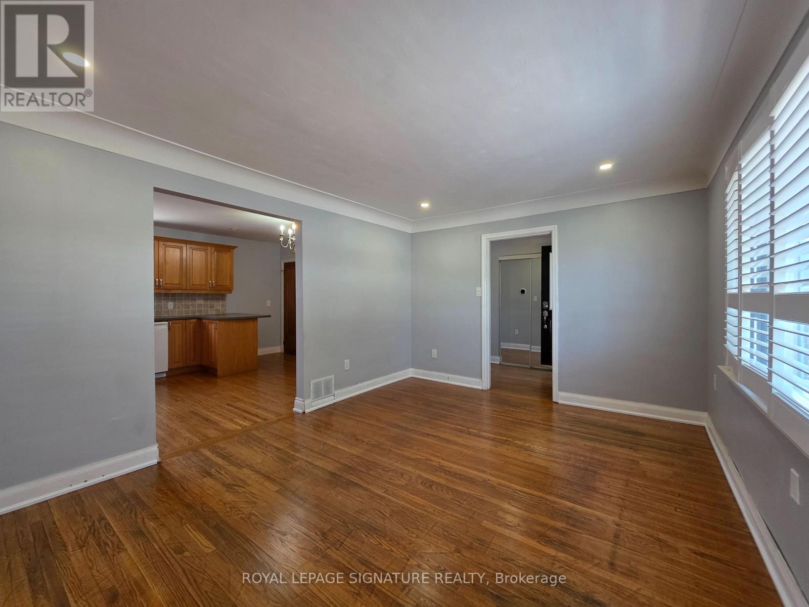 A spacious room with wooden flooring and white walls.