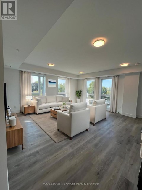 A spacious living room with white furniture and a large window.