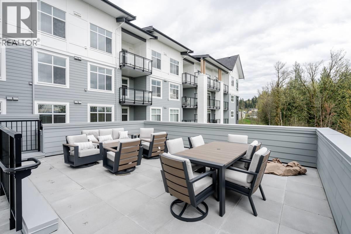 A patio with a table and chairs is in front of a building with a balcony.