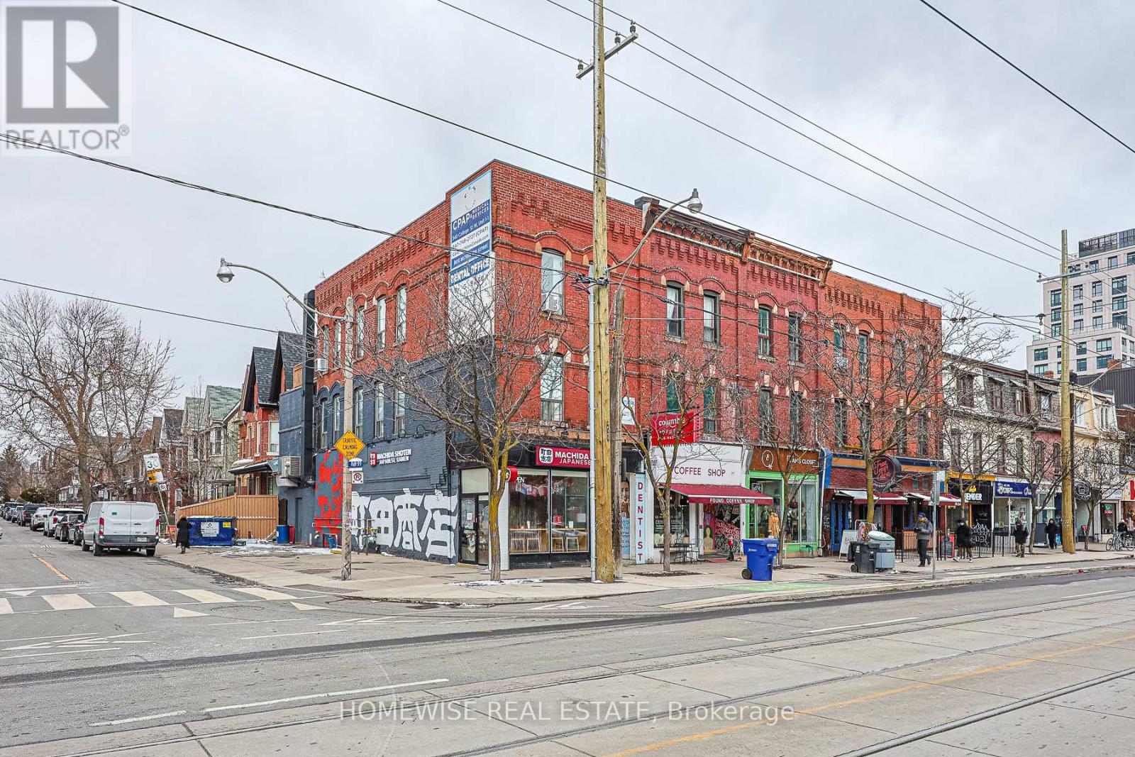 A street view of a red brick building with a Homewise Real Estate Brokerage sign on it.