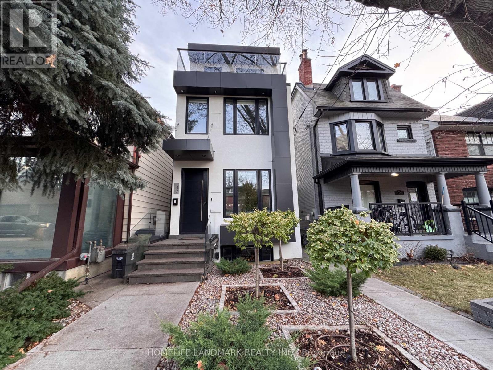 A house with a black and white facade is surrounded by a garden.