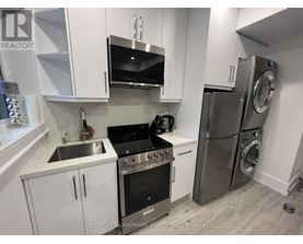A modern kitchen with white cabinets and stainless steel appliances.