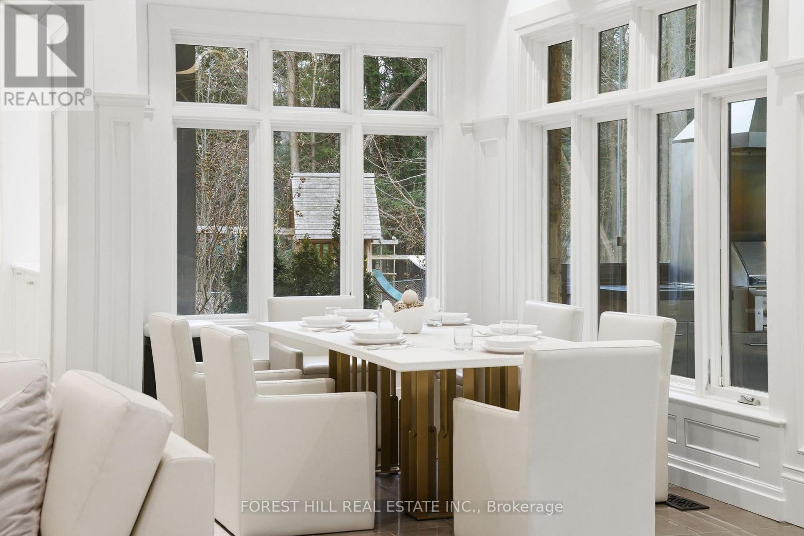 A dining room with a table set for six with a view of the trees outside the window.