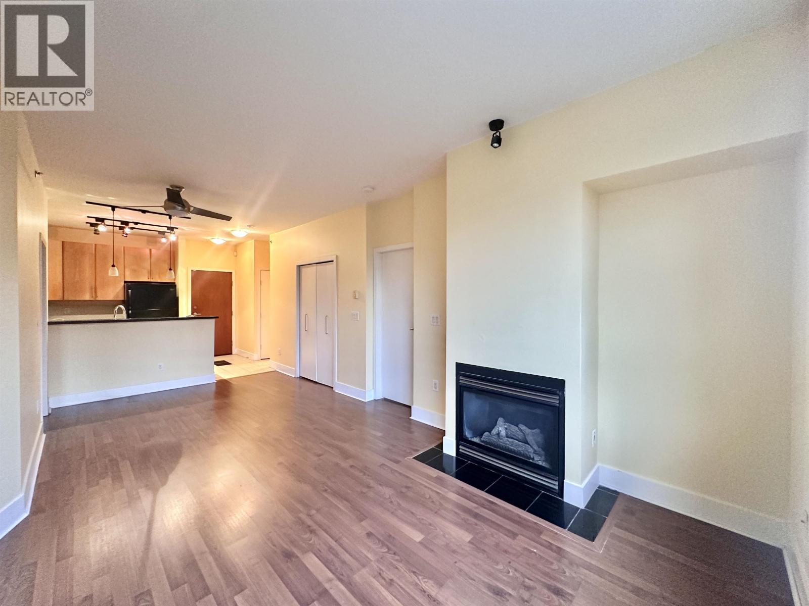 A living room with a fireplace and a ceiling fan.