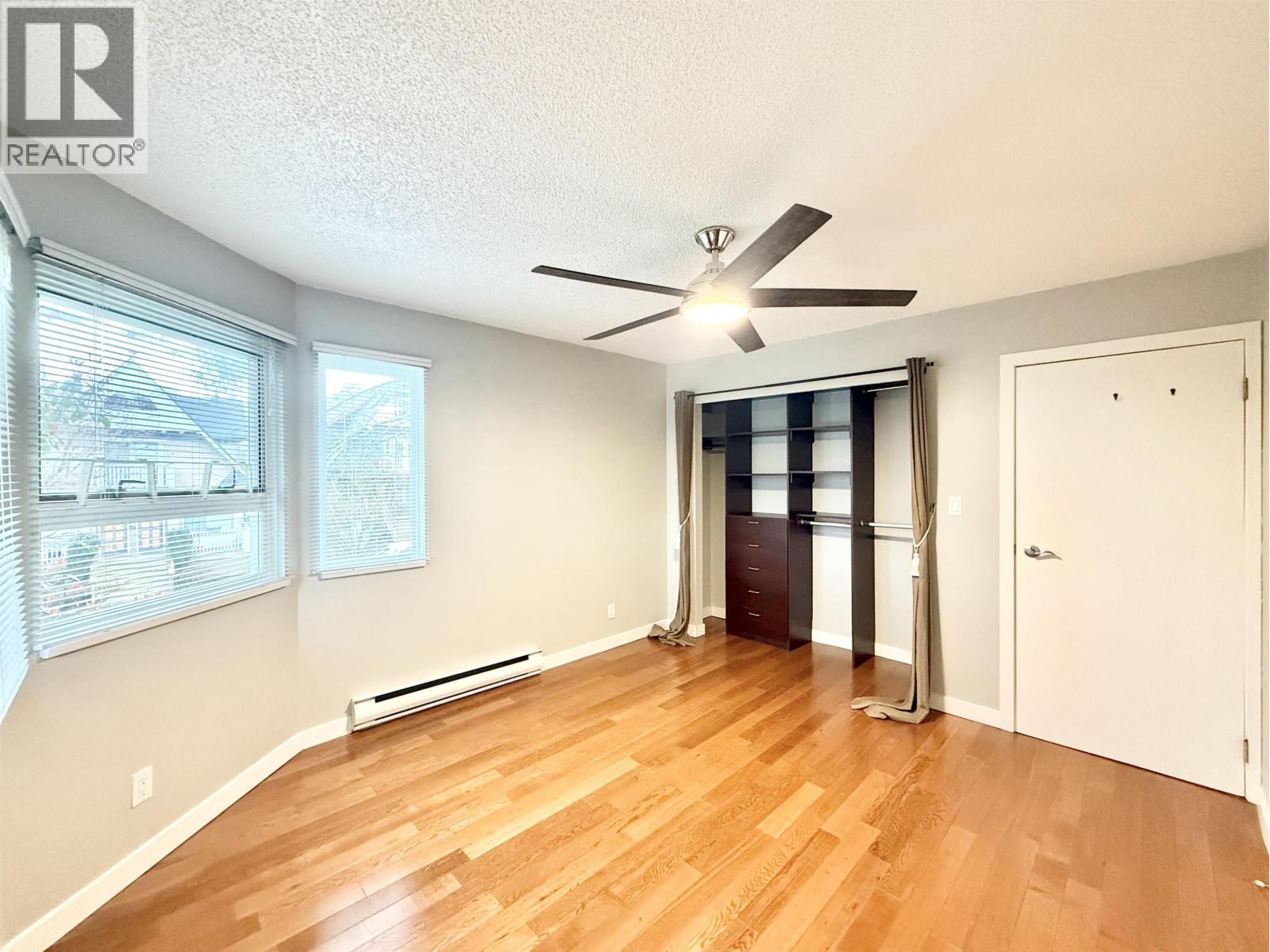 A room with a ceiling fan and wooden flooring.