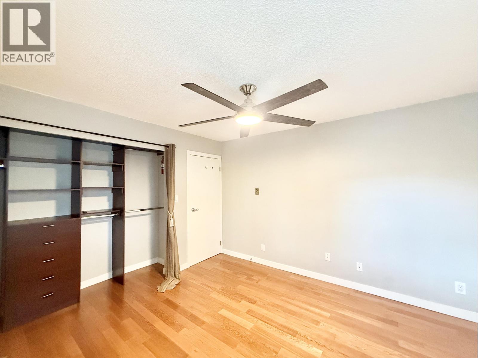 A room with a ceiling fan and wooden flooring.
