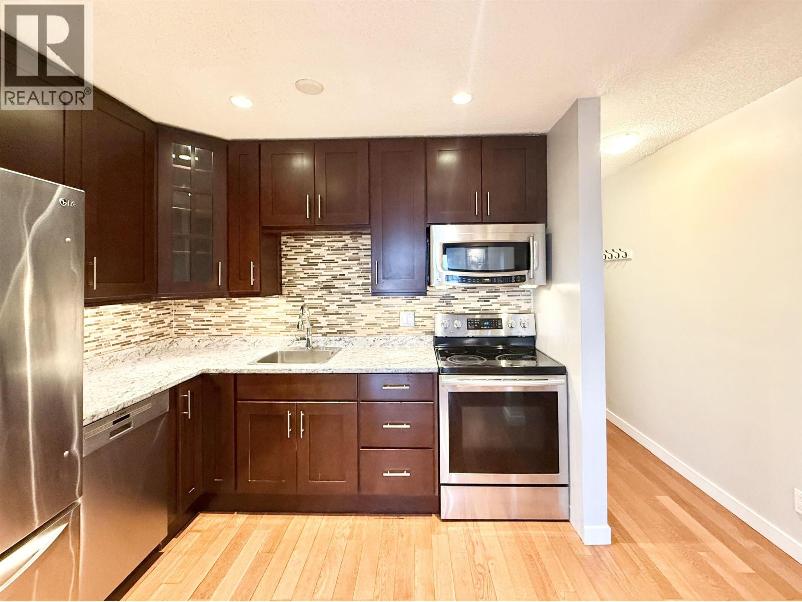 A modern kitchen with dark wood cabinets and stainless steel appliances.