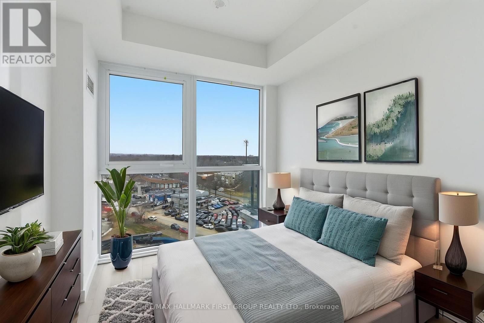 A bedroom with a large bed and a view of a parking lot through the window.