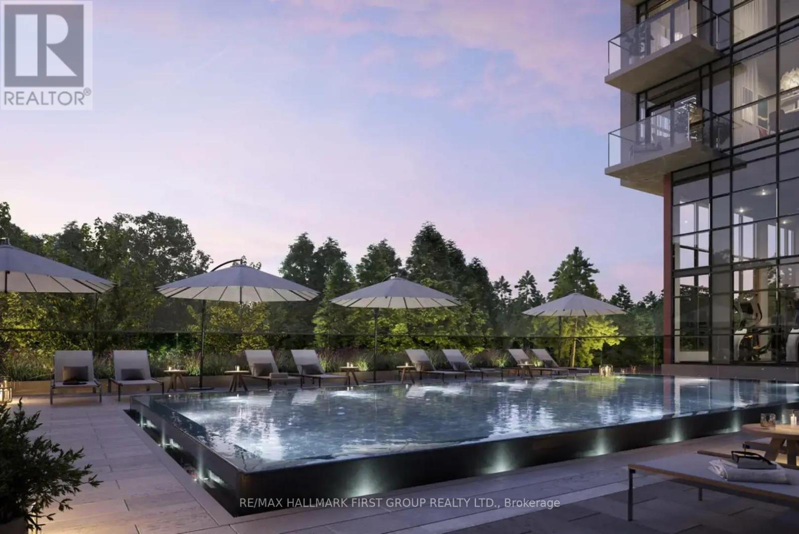 A pool surrounded by chairs and umbrellas in front of a building.
