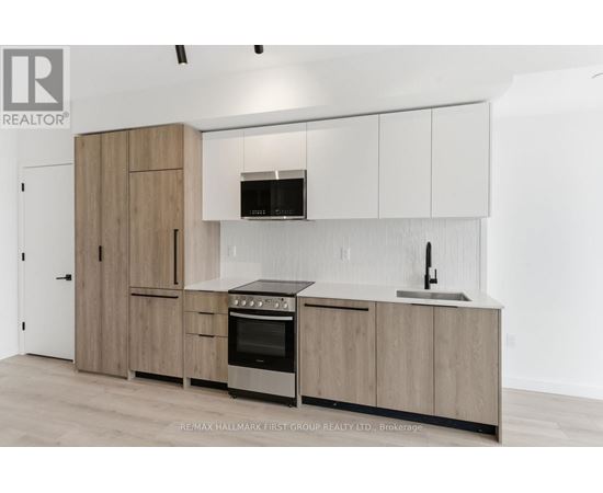 A kitchen with wooden cabinets and a black microwave above the stove.