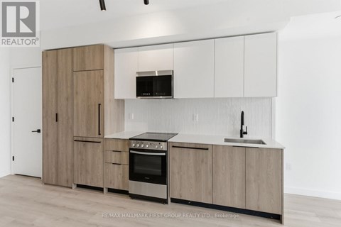 A kitchen with wooden cabinets and a black microwave above the stove.