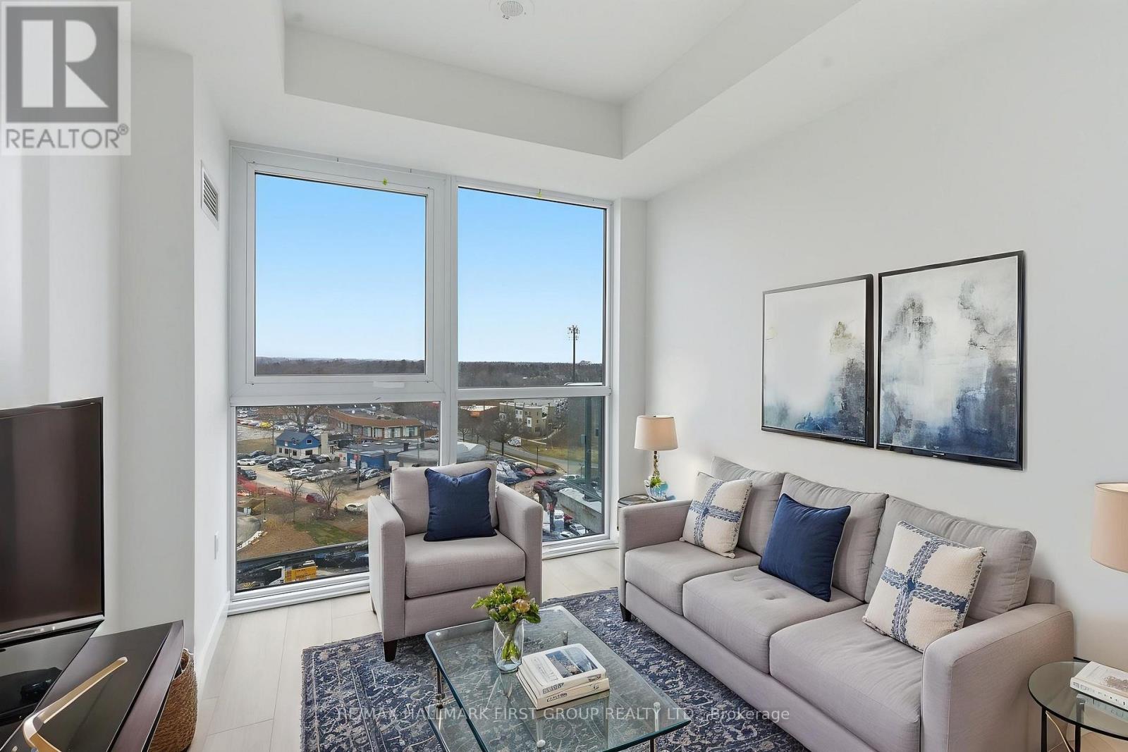 A living room with a couch, chair, and a large window overlooking a cityscape.