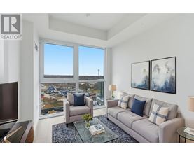 A living room with a couch, chair, and a large window overlooking a cityscape.