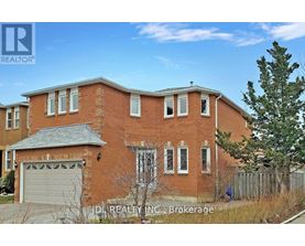 A red brick house with a garage door and a tree in front.