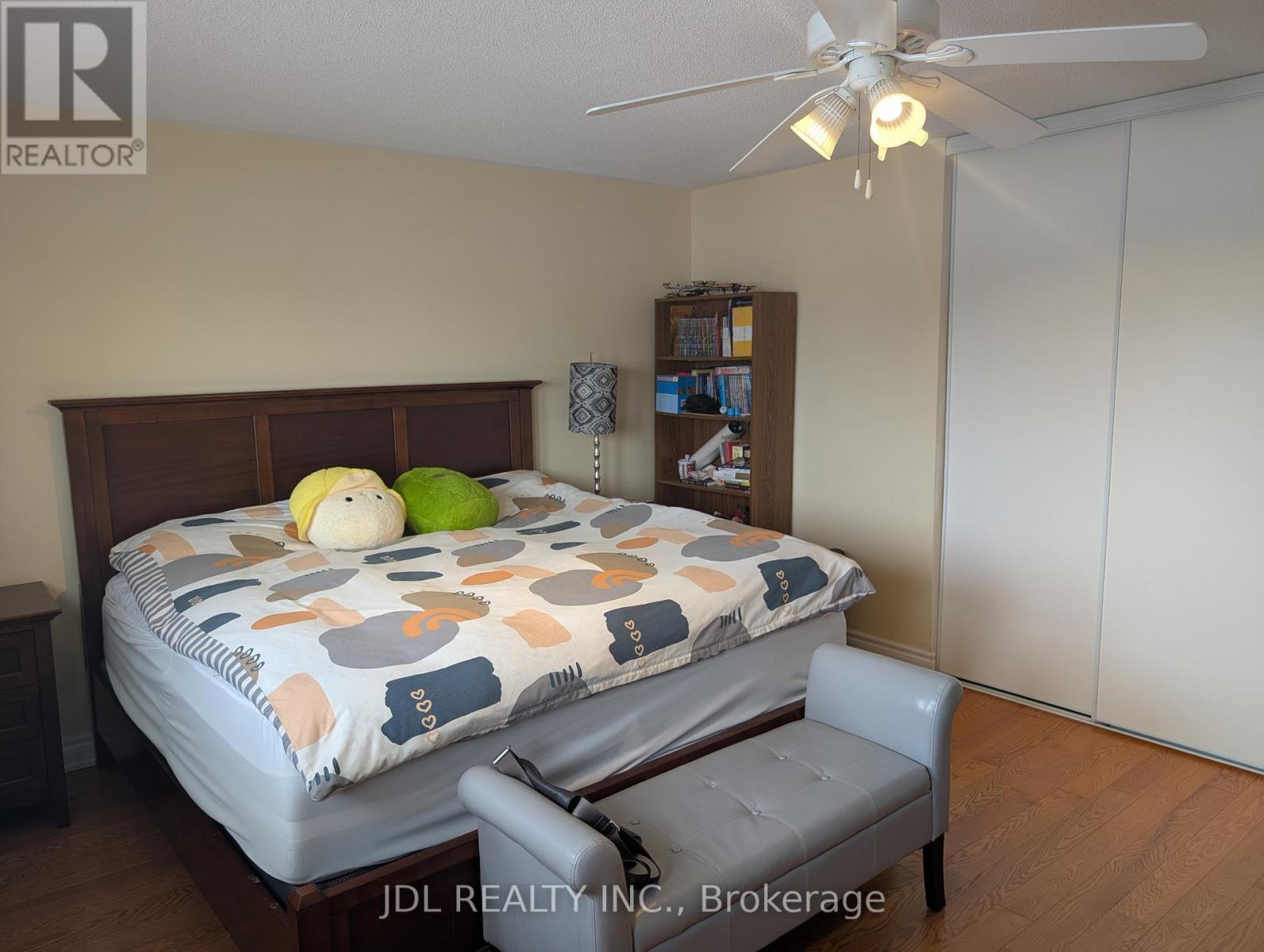 A bedroom with a bed, chair, and a ceiling fan.