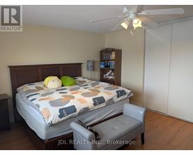 A bedroom with a bed, chair, and a ceiling fan.