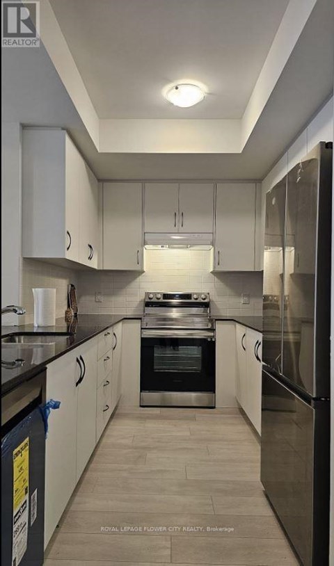 A kitchen with white cabinets and a black refrigerator.